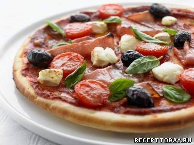 Пицца с ветчиной помидорами и оливками.